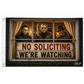 A rectangular novelty flag or banner with a horror-themed window scene showing three masked figures behind dark wood framing, with a large sign reading 'NO SOLICITING WE'RE WATCHING.' The left edge has a white header with metal grommets, and a small 'Funny Chicago Hats' mark appears in the lower right corner.