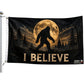 A novelty flag featuring a silhouette of Bigfoot walking in a forest under a large full moon, with the text 'I BELIEVE' at the bottom. The flag is shown hanging from a white flagpole against a plain white background.
